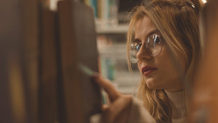 A woman looking through books at a library or bookstore.